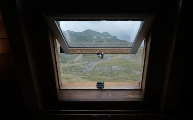 Fenêtre de toit vue depuis les combles, ouverte sur le paysage