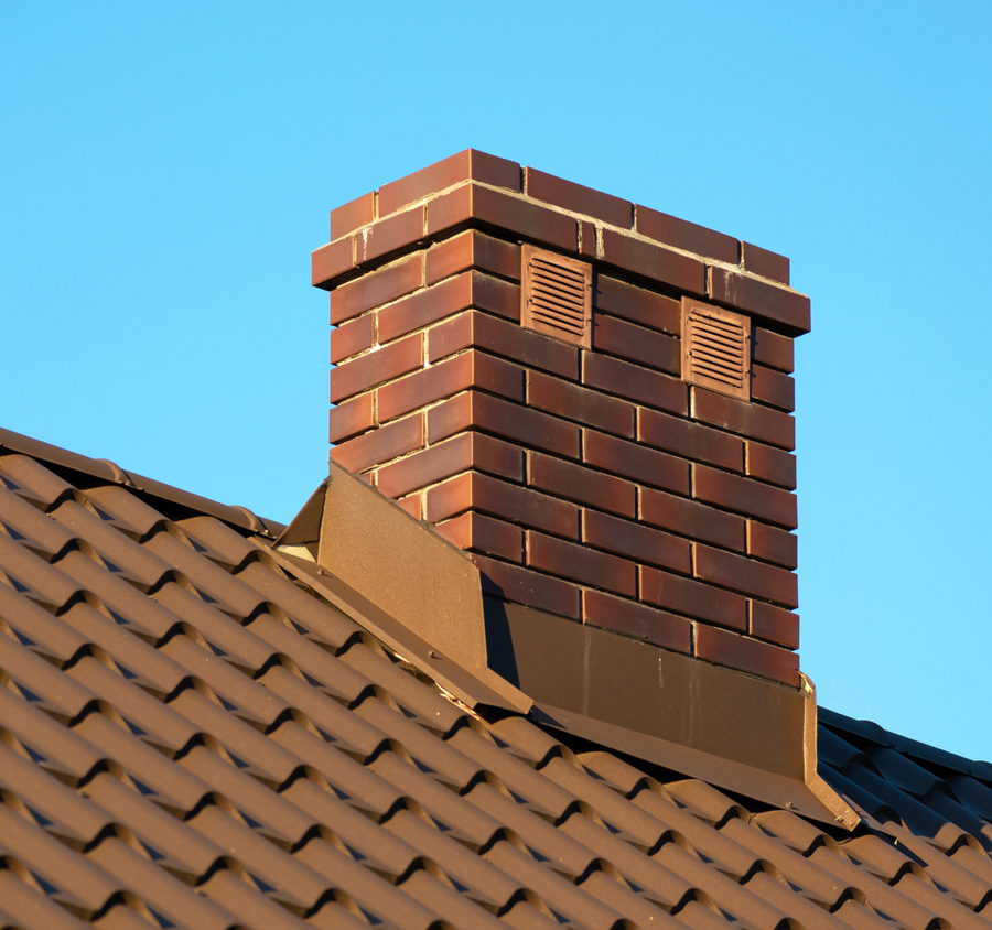 Souche de cheminée en briques neuves montée sur une couverture en tuiles