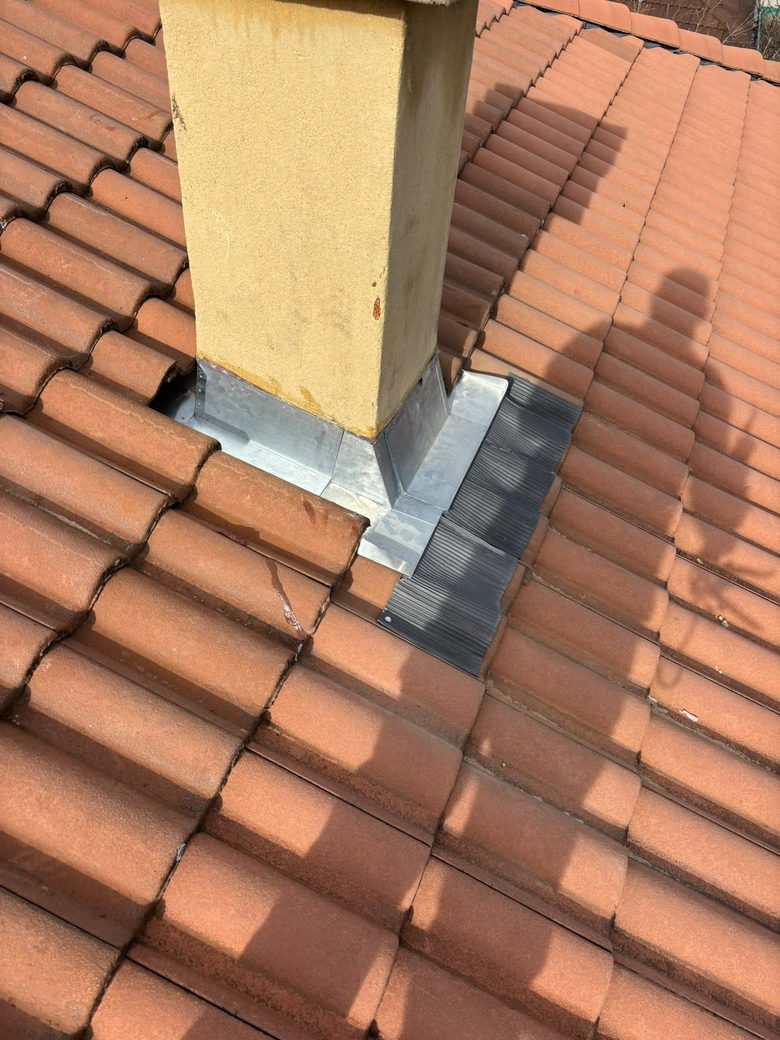 Solin en zinc neuf posé au pied d'une souche de cheminée sur une toiture en tuiles