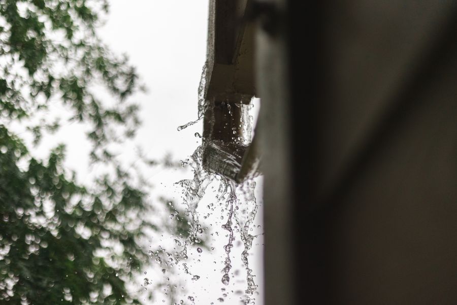 Eau de pluie s'écoulant dans une descente de gouttière en zinc